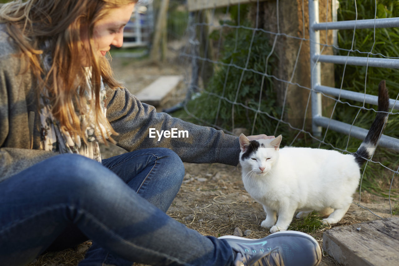 YOUNG WOMAN TOUCHING HORSE OUTDOORS