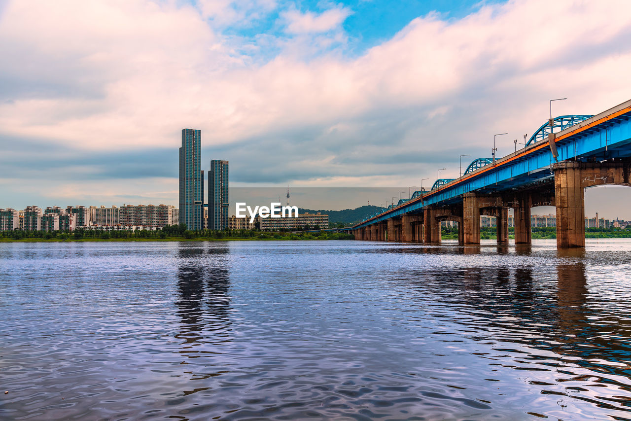 VIEW OF BRIDGE OVER RIVER WITH CITY IN BACKGROUND