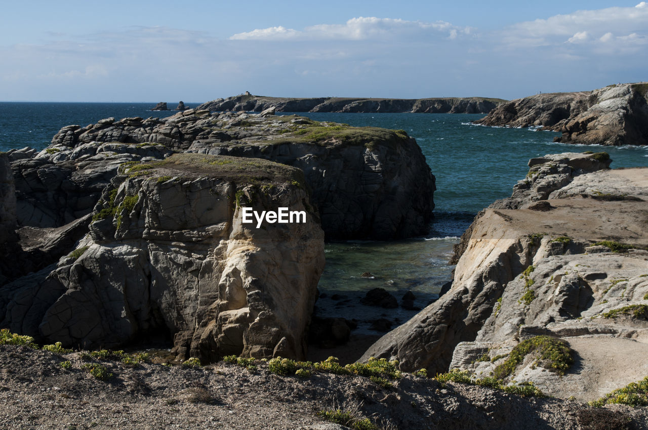 Scenic view of sea and cliff against sky