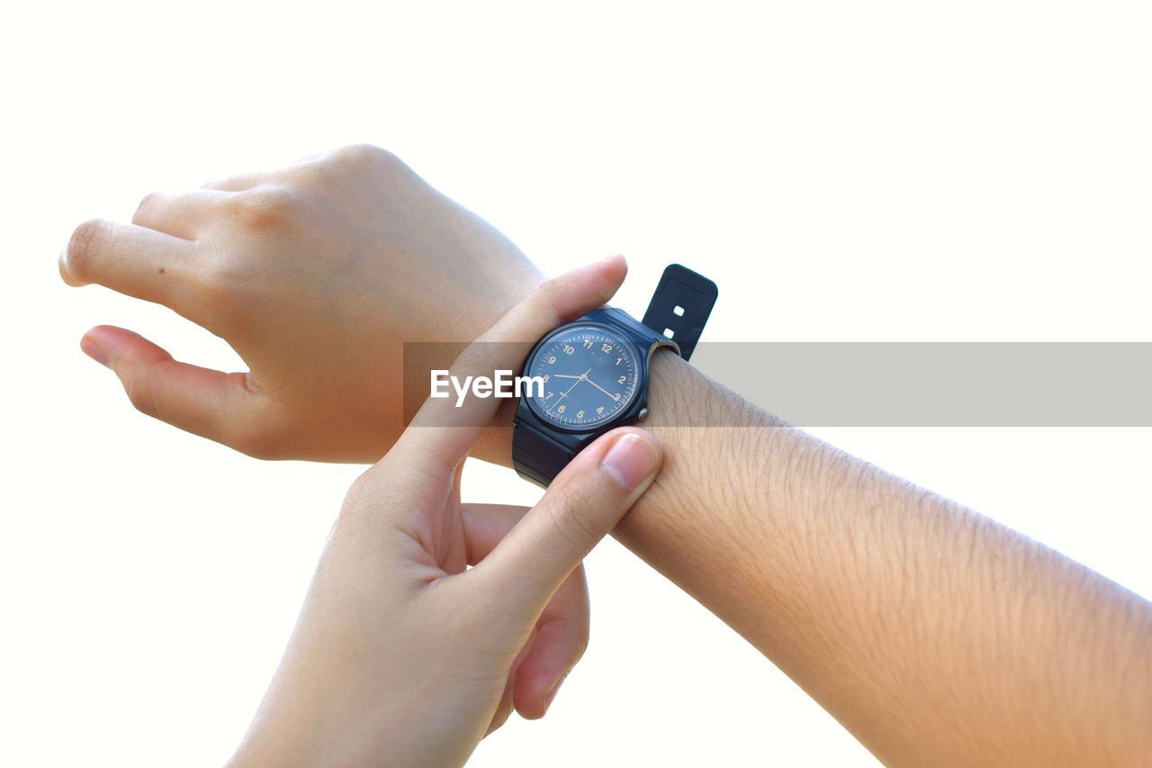 Close-up of woman holding checking the time over white background