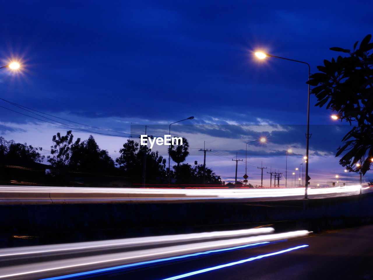 LIGHT TRAILS ON ROAD AGAINST SKY