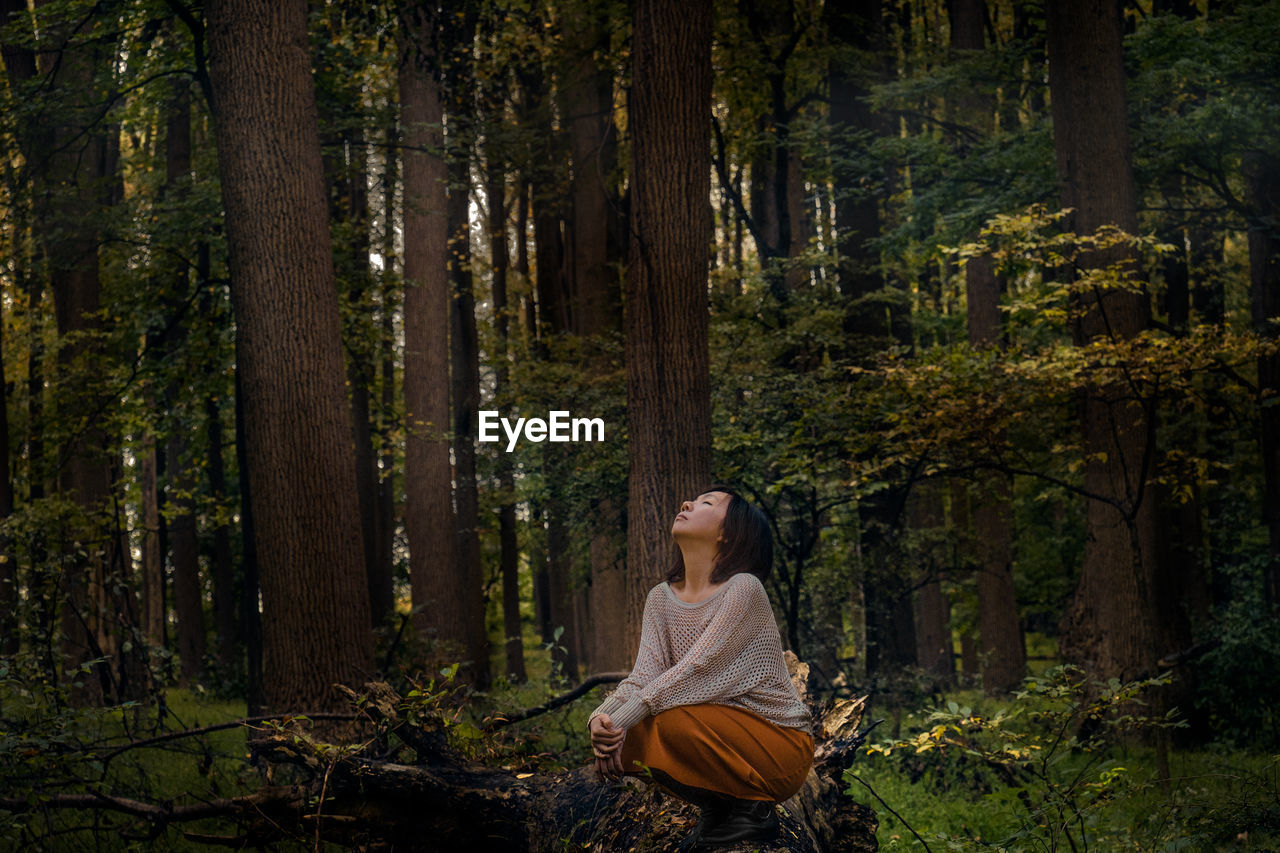 Woman looking up when sitting in forest