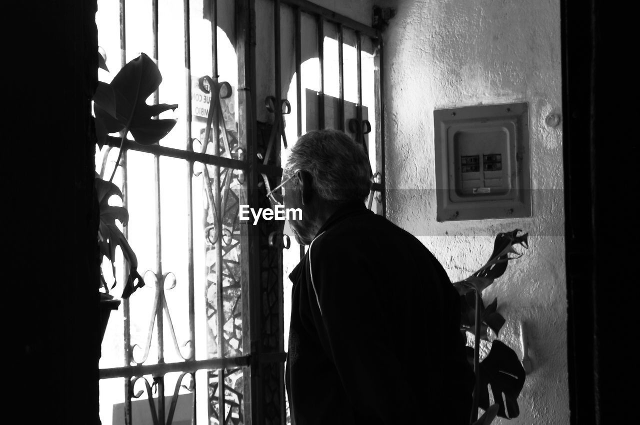 Rear view of man standing by window at home