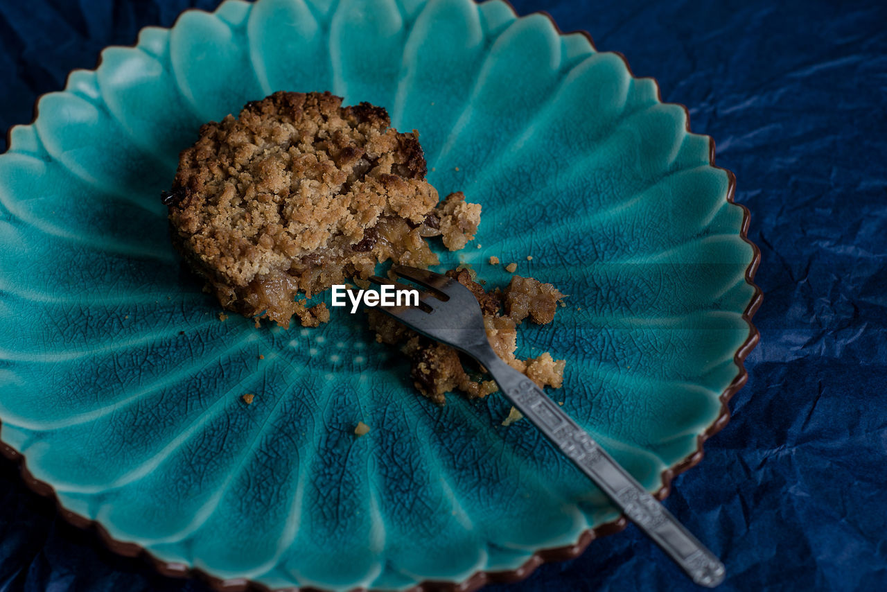 High angle view of baked, half eaten apple pie on a green leaf shaped plate