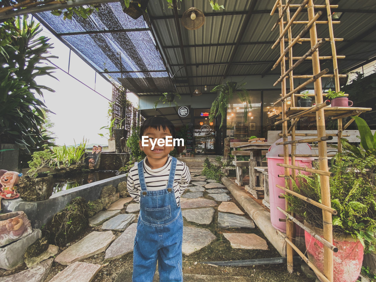 childhood, one person, child, looking at camera, men, portrait, standing, smiling, casual clothing, happiness, front view, full length, emotion, architecture, day, lifestyles, nature, leisure activity, innocence, plant, female, cute, outdoors, built structure, clothing, toddler, growth, cheerful