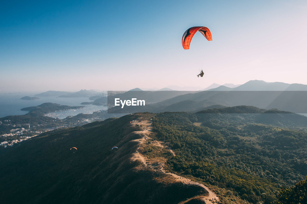 PEOPLE PARAGLIDING AGAINST SKY