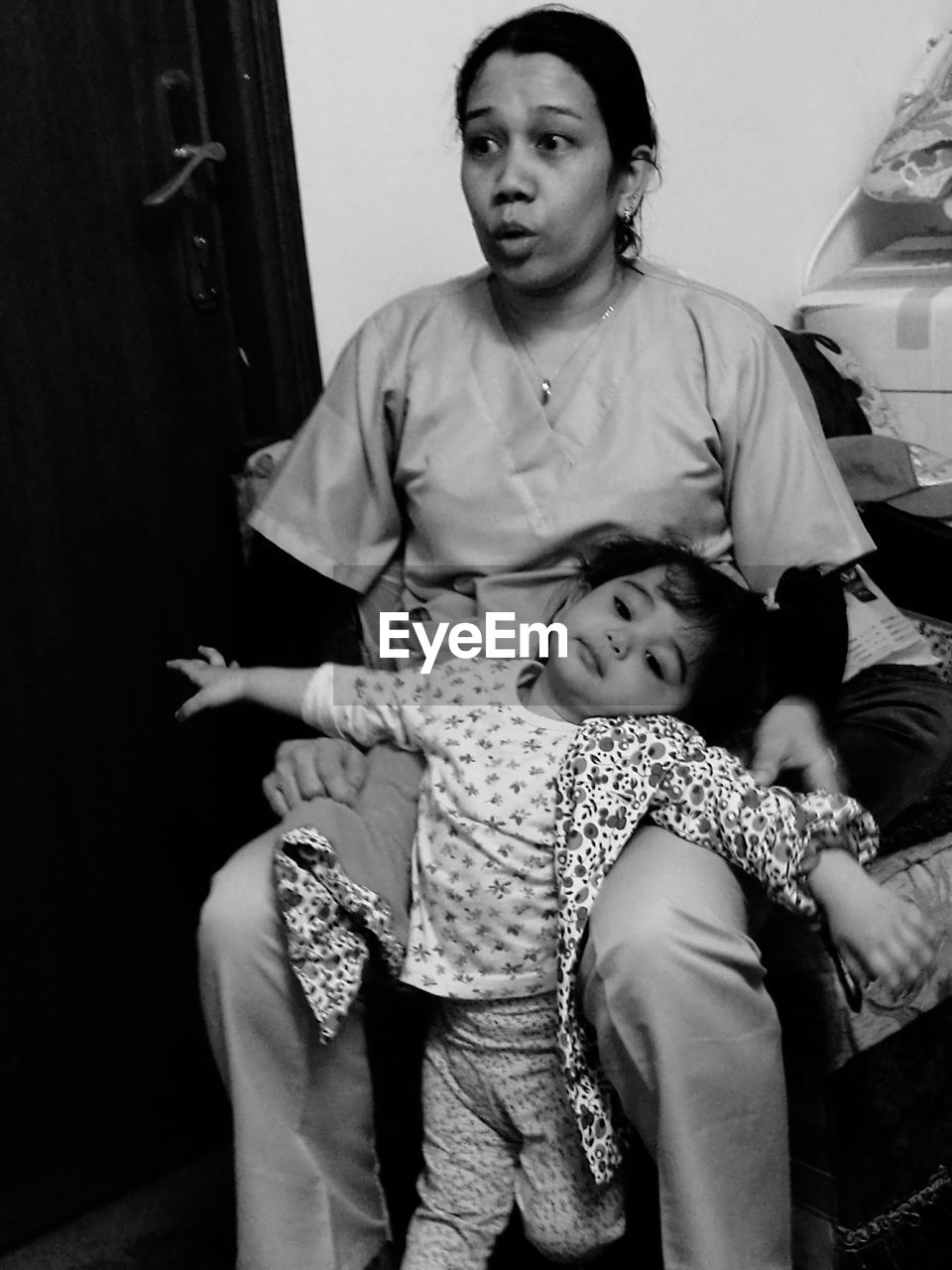 Mother sitting with daughter on chair at home