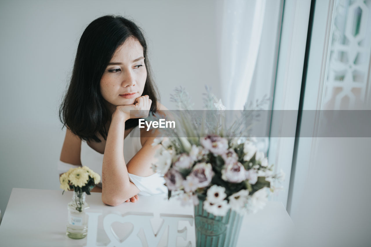 Woman sitting by flowers at home