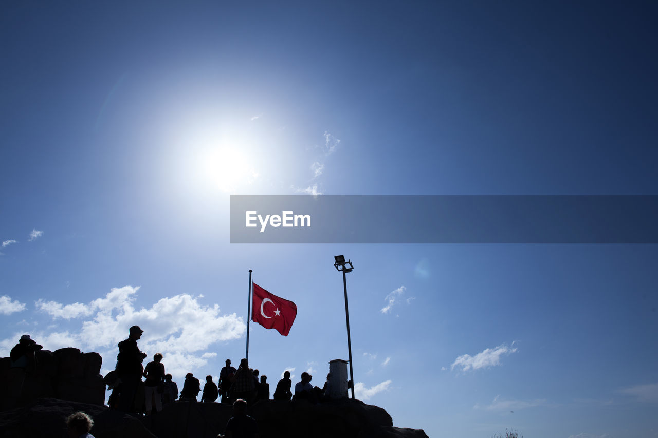 Low angle view of people standing by turkish flag against sky