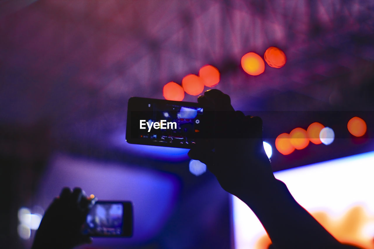 Close-up of hand holding smart phone at music concert