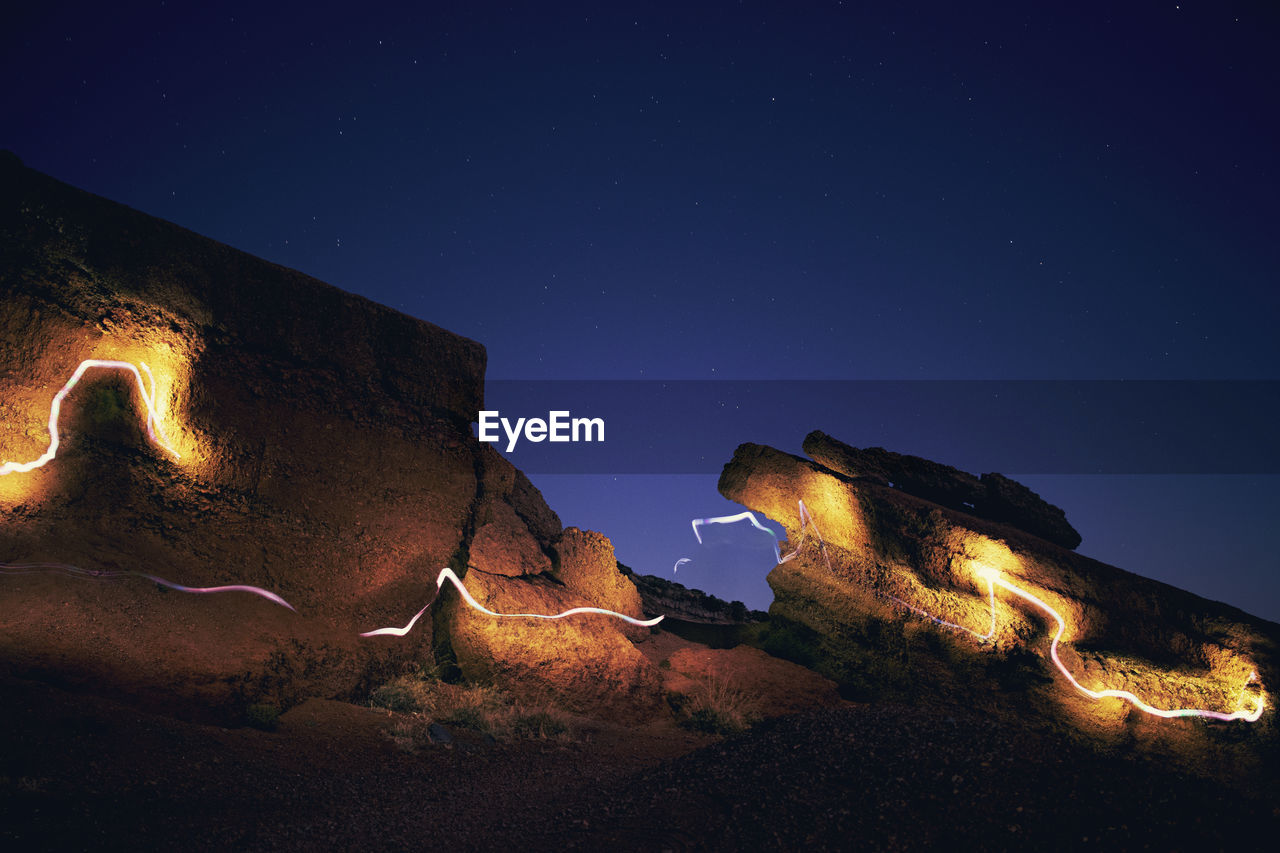 Low angle view of illuminated rocks against sky at night