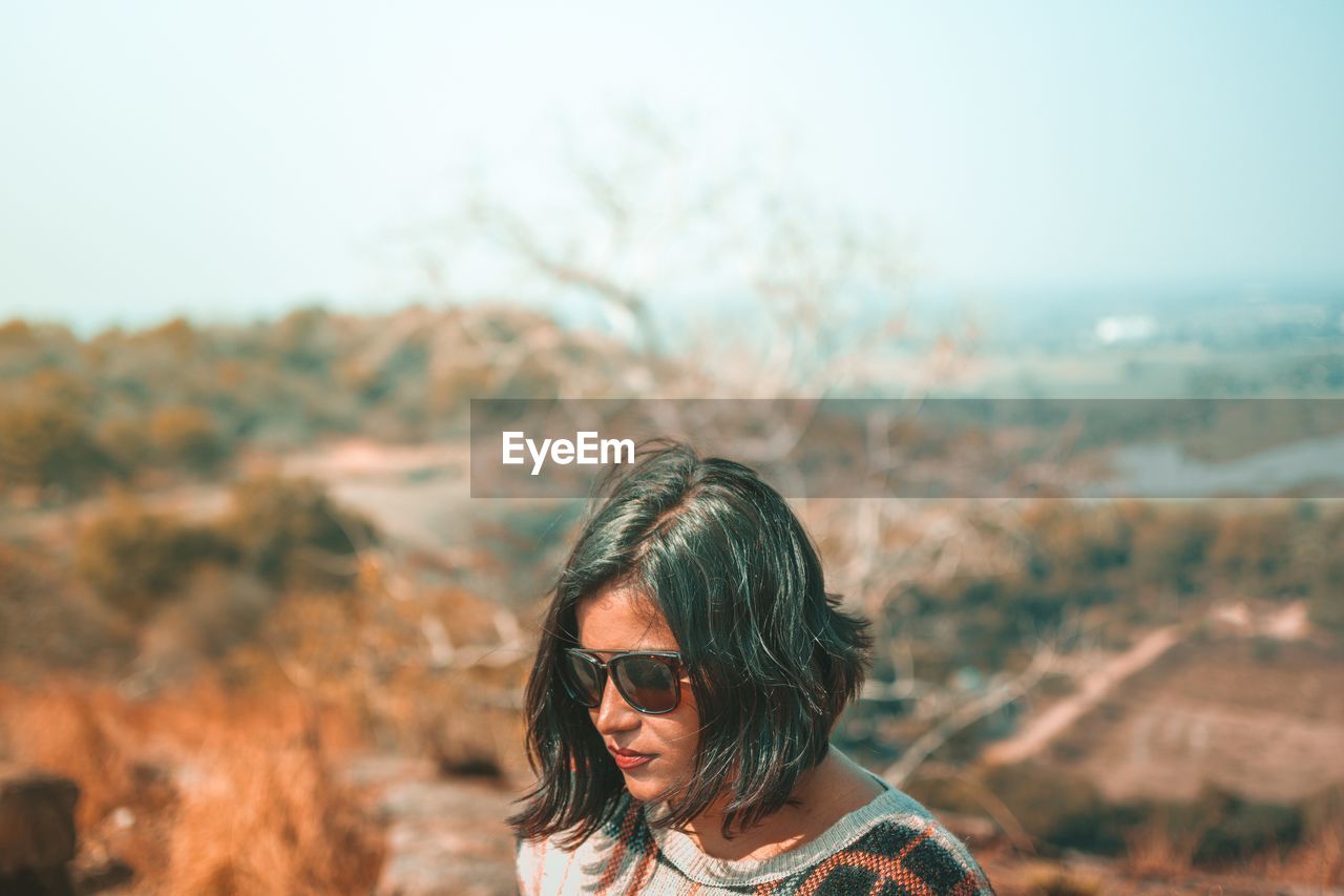 Woman wearing sunglasses standing against sky