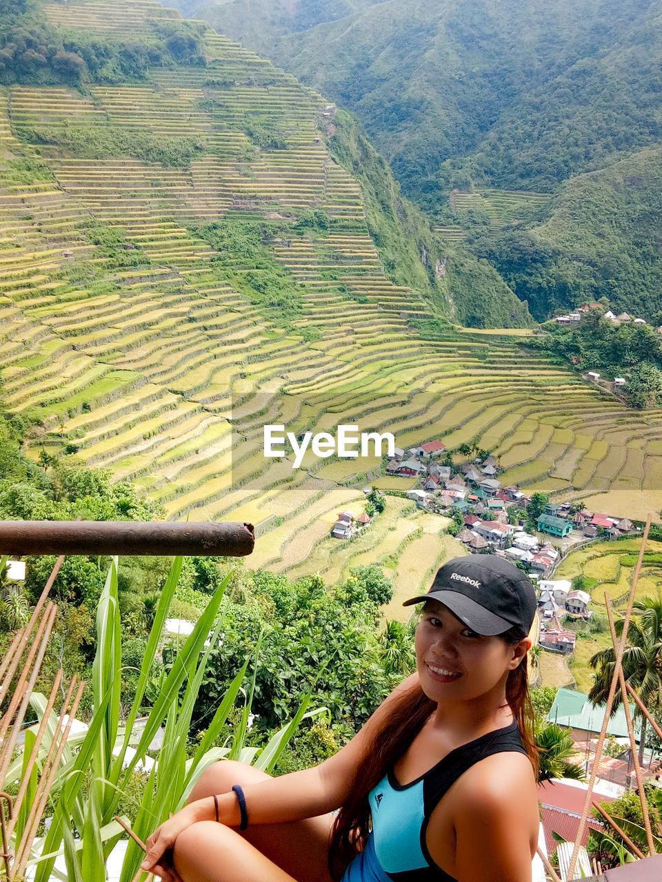 PORTRAIT OF SMILING YOUNG WOMAN STANDING ON AGRICULTURAL LAND