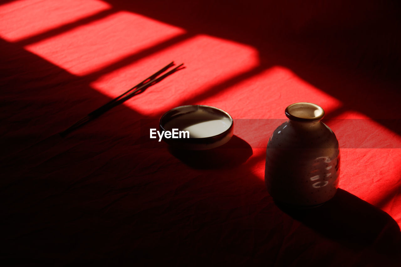 red, shadow, still life photography, darkness, light, drink, food and drink, table, indoors, no people, black, high angle view, pink, close-up, refreshment, lighting, macro photography, wood, still life, bottle, container