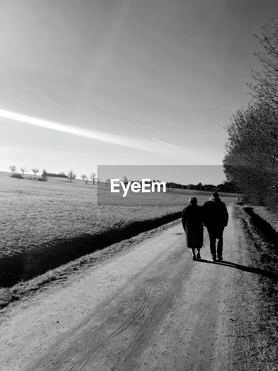 REAR VIEW OF COUPLE WALKING ON ROAD