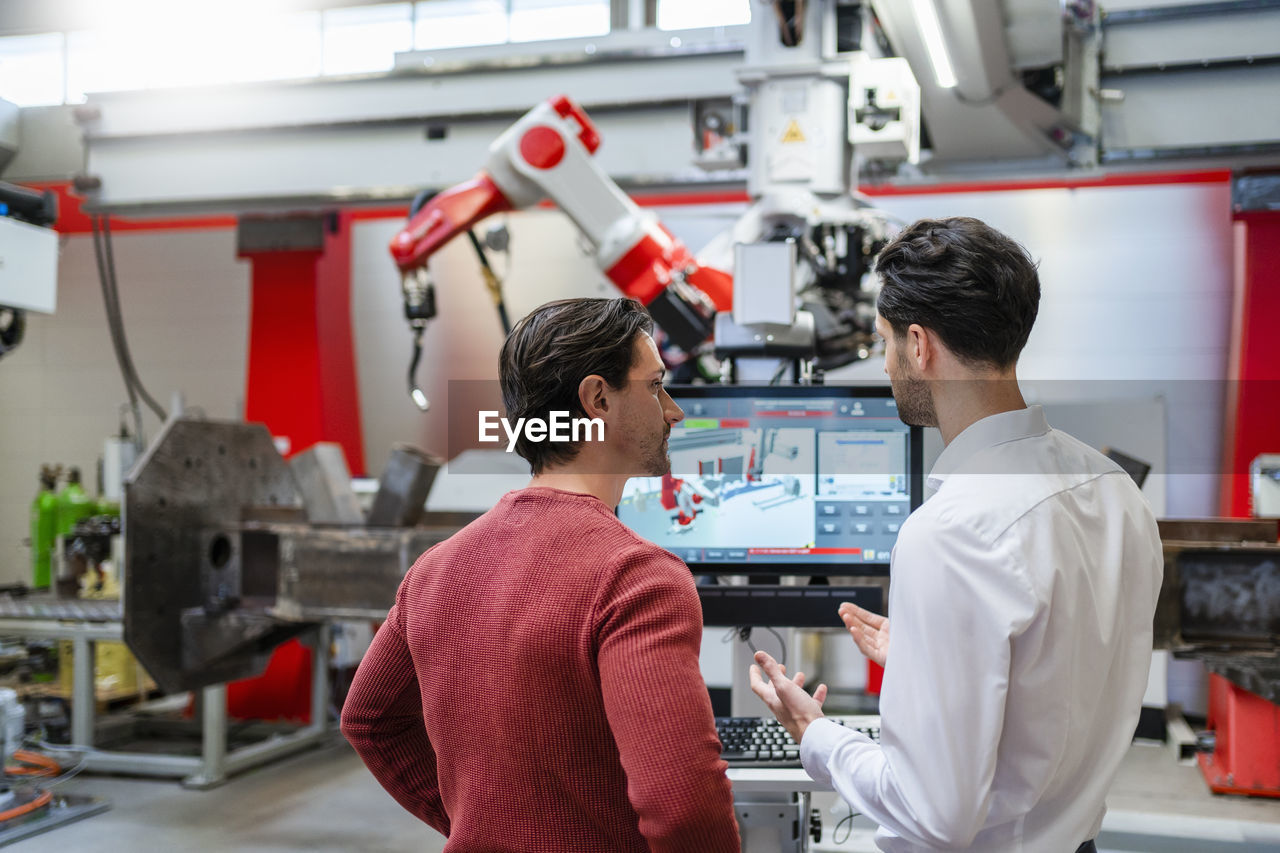 Engineers discussing with each other at robot factory
