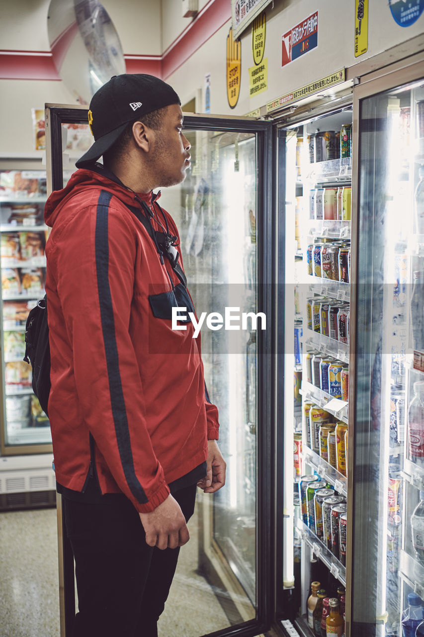 SIDE VIEW OF A YOUNG MAN LOOKING AT STORE