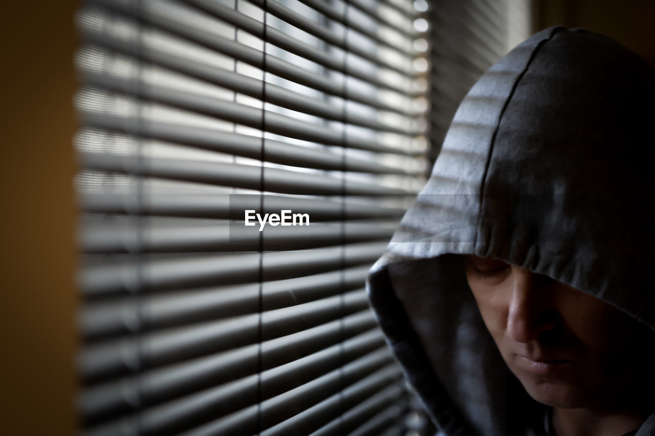 Close-up of man standing against window