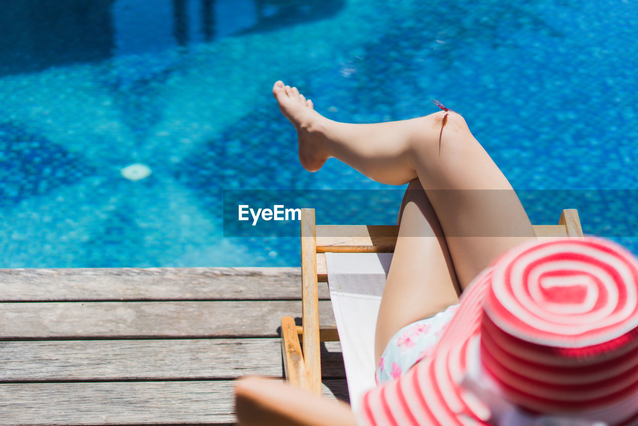 High angle view of woman relaxing at poolside during sunny day