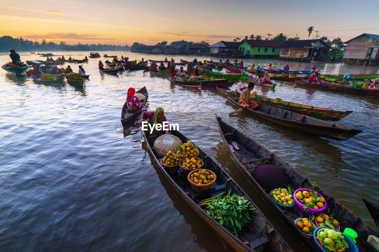 High angle view of people with food sitting in boats over river at sunset