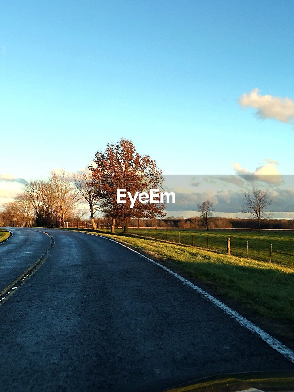 Empty road on field against cloudy sky