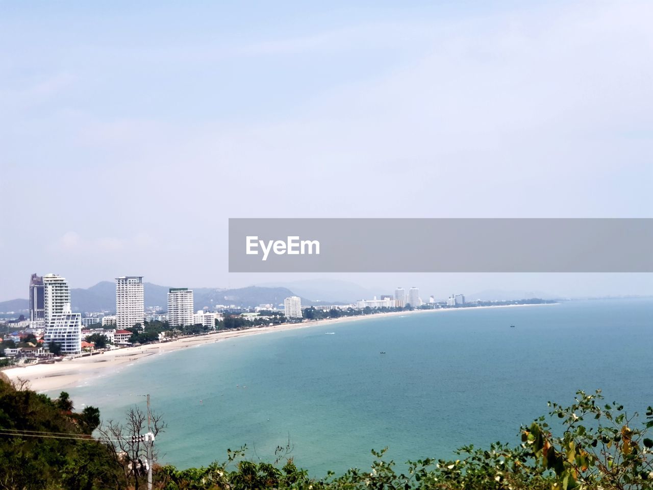 HIGH ANGLE VIEW OF CITY BY SEA AGAINST SKY