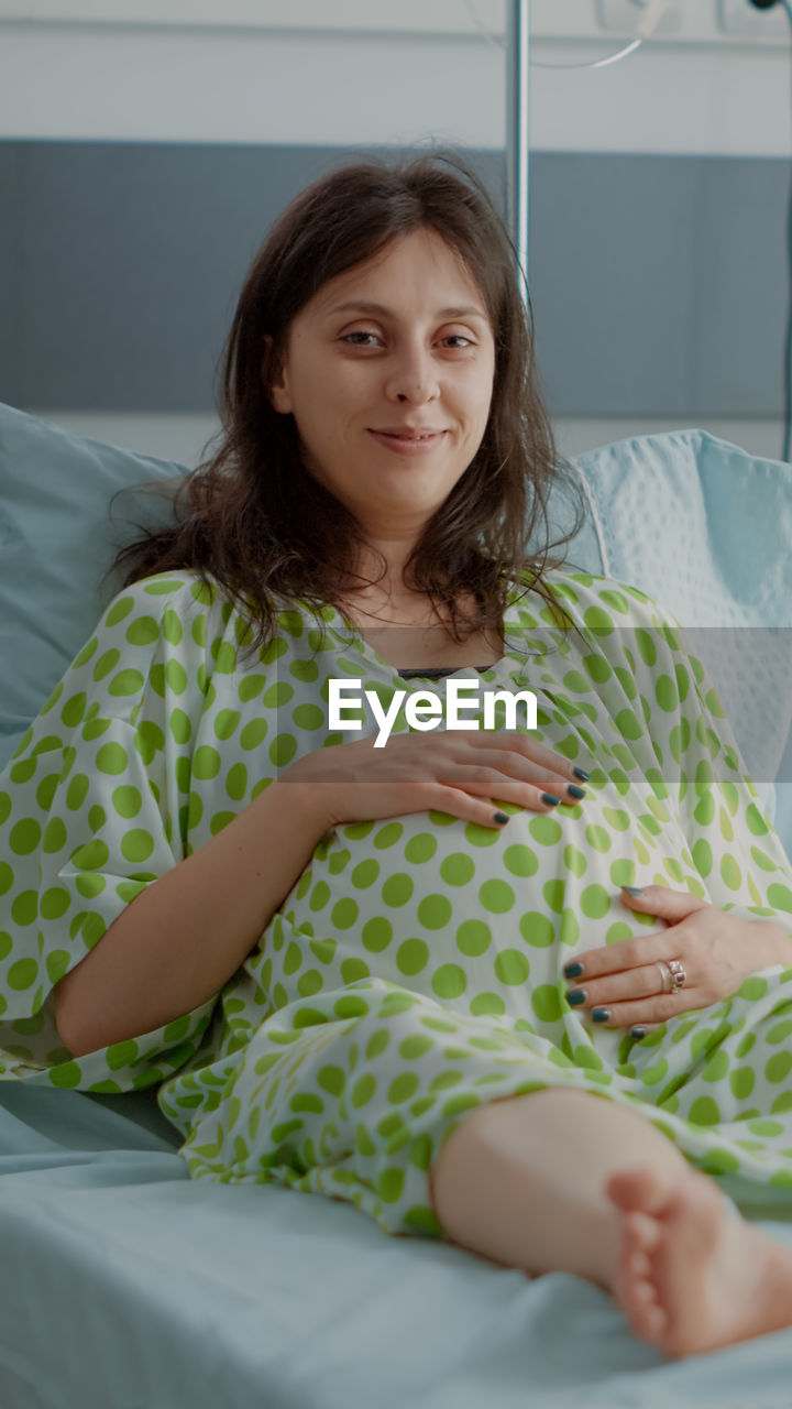 portrait of smiling woman sitting on bed