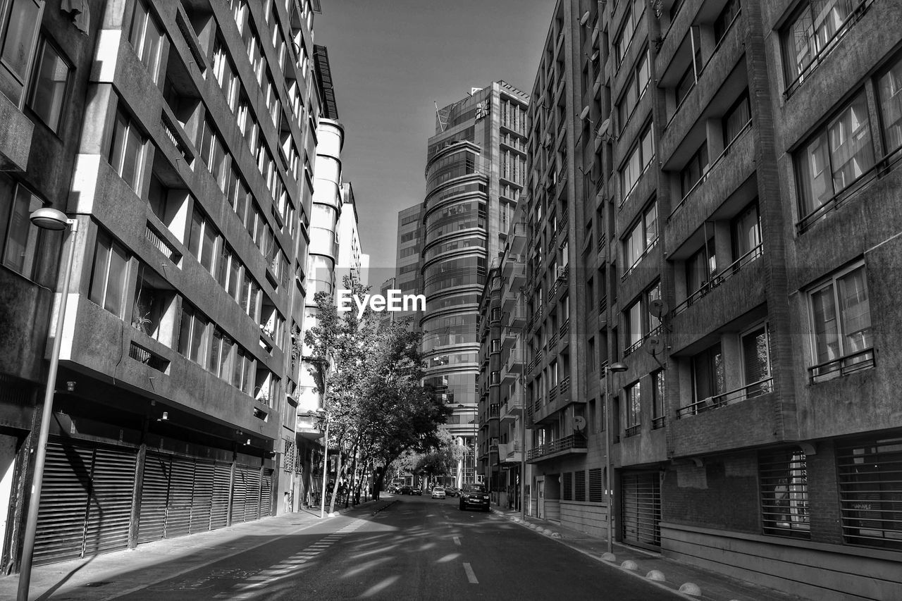 Empty road amidst buildings in city