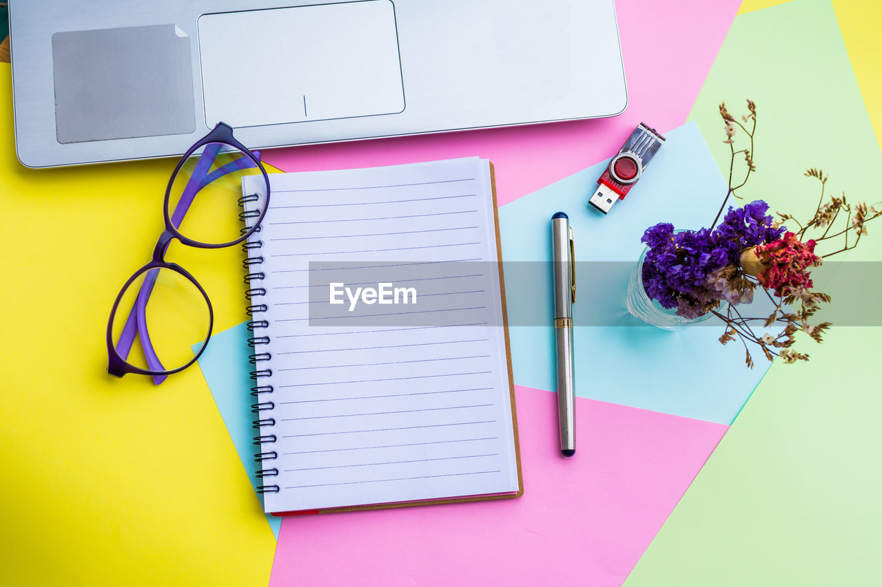 Spiral notebook with laptop on colorful papers