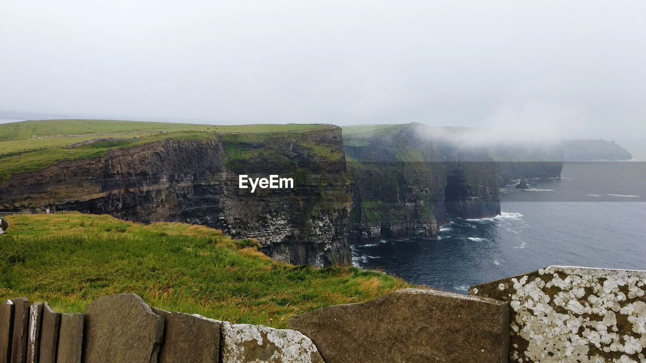 SCENIC VIEW OF WATERFALL ON CLIFF AGAINST SKY