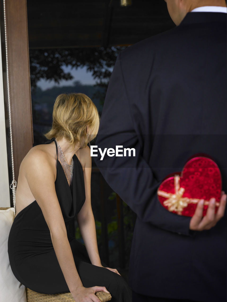 Rear view of man with gift standing against woman in ceremony