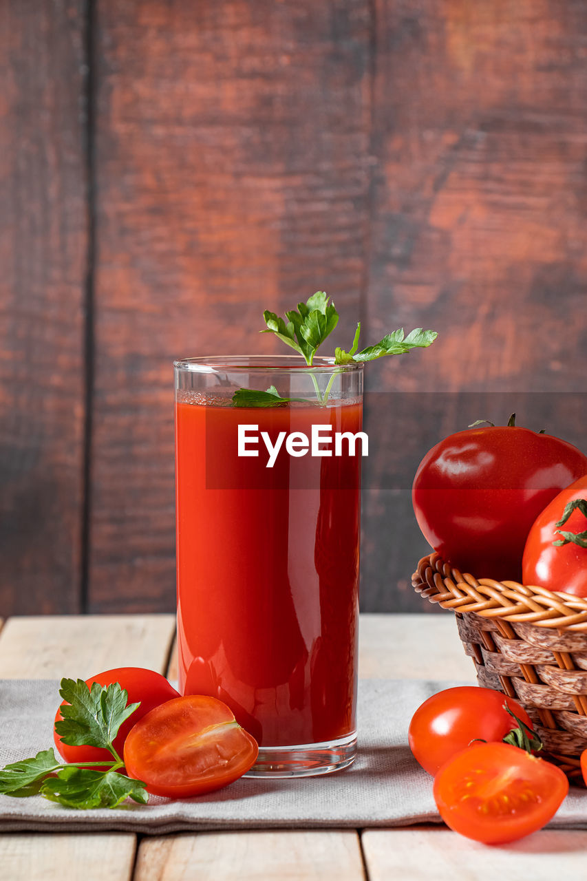 Fresh tomato juice on a wooden rustic background. organic vegetable drink with parsley.