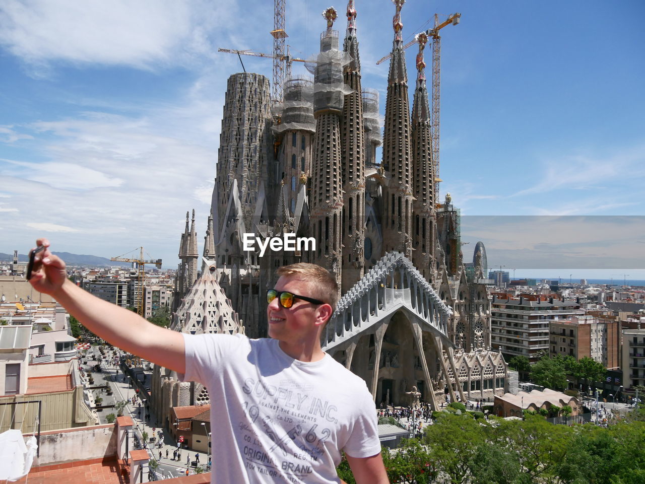 MAN WITH ARMS OUTSTRETCHED AGAINST BUILDINGS