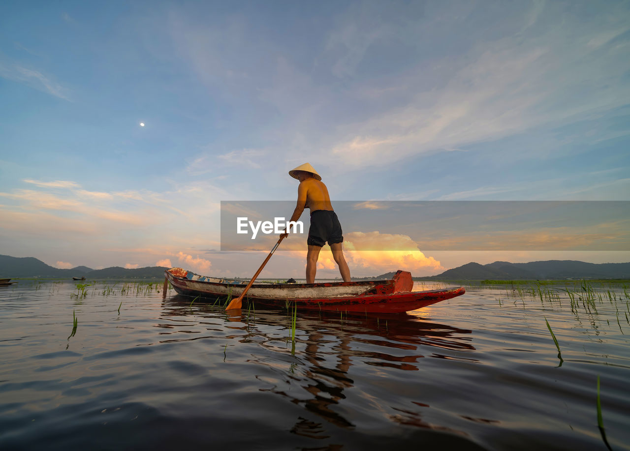 MAN FISHING IN BOAT AT SUNSET