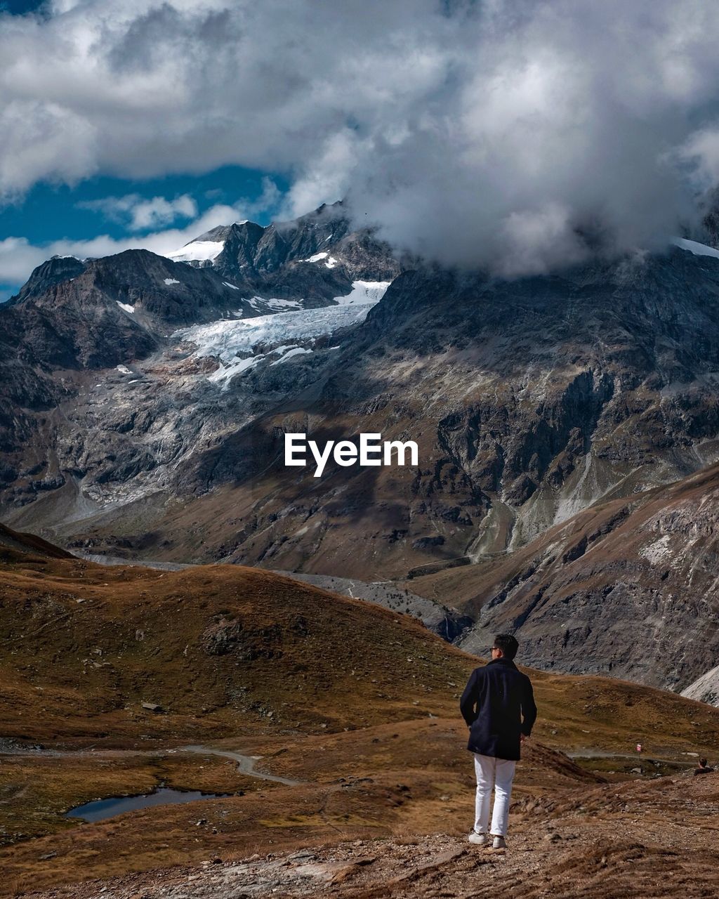 Rear view of man standing on mountain against sky