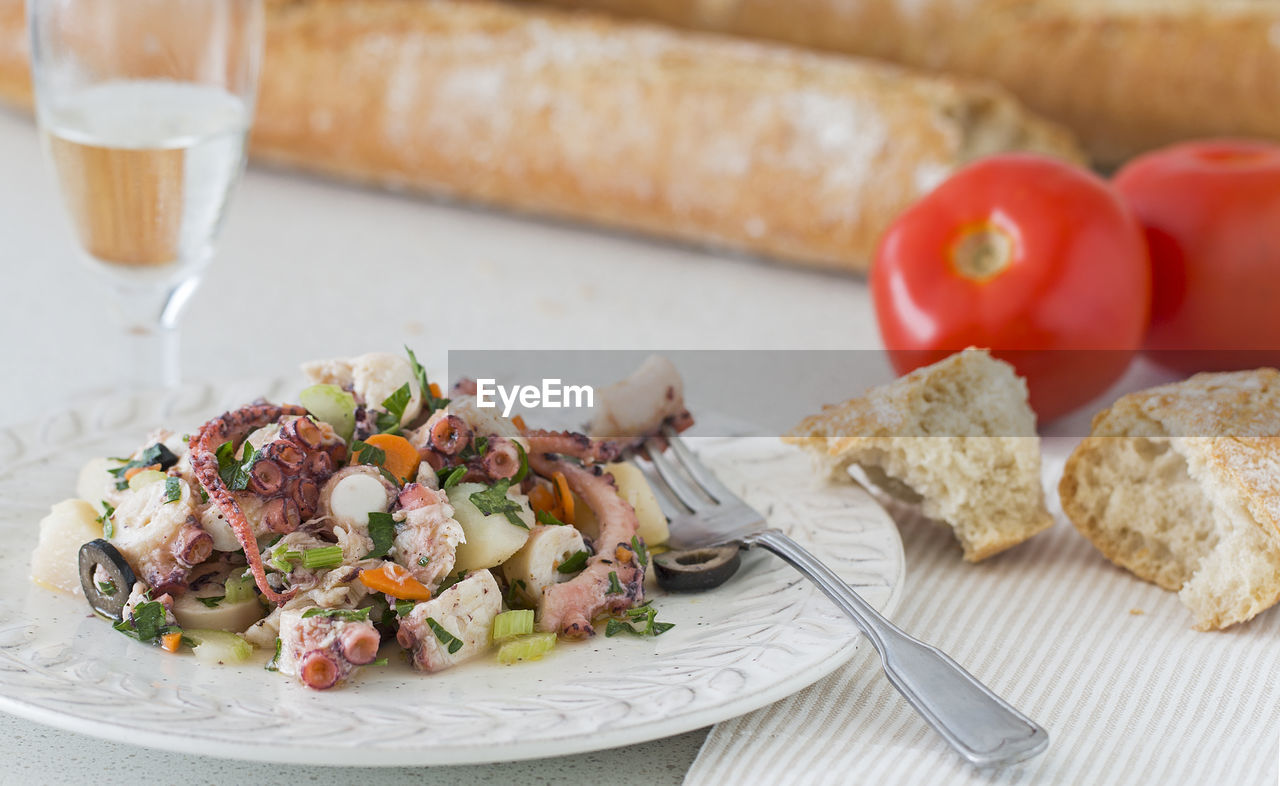 Octopus bread, tomatoes and a glass of white wine.