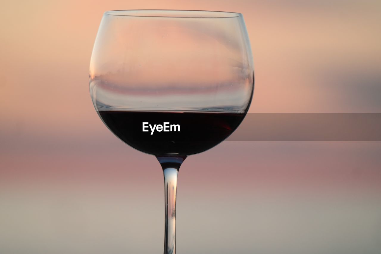 Close-up of wineglass on table against sky during sunset