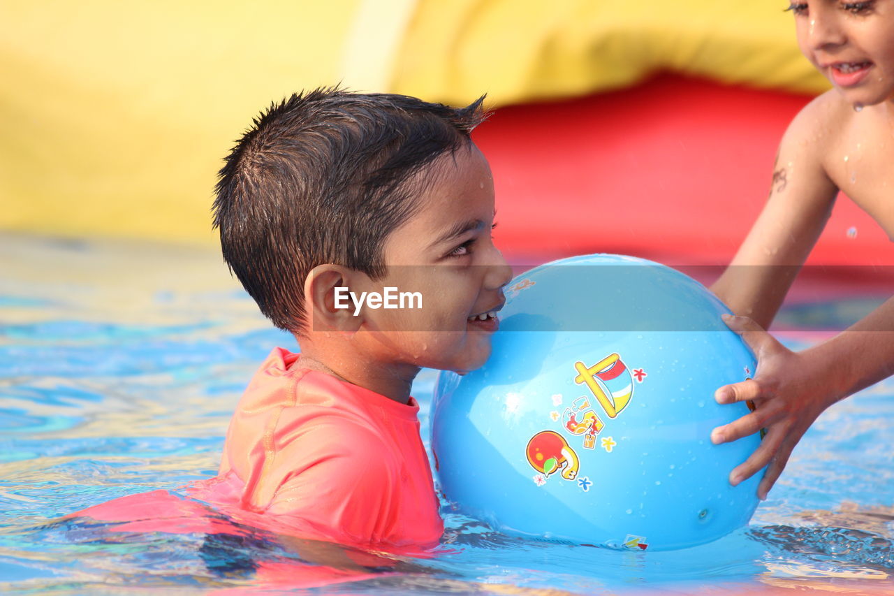 Side view of boy playing with friend in swimming pool