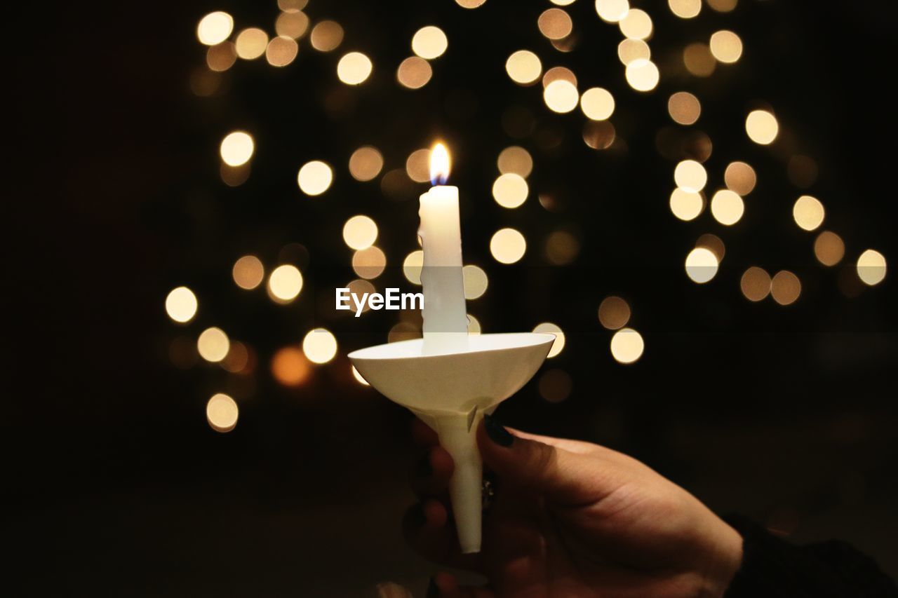 Close-up of hand holding illuminated candle