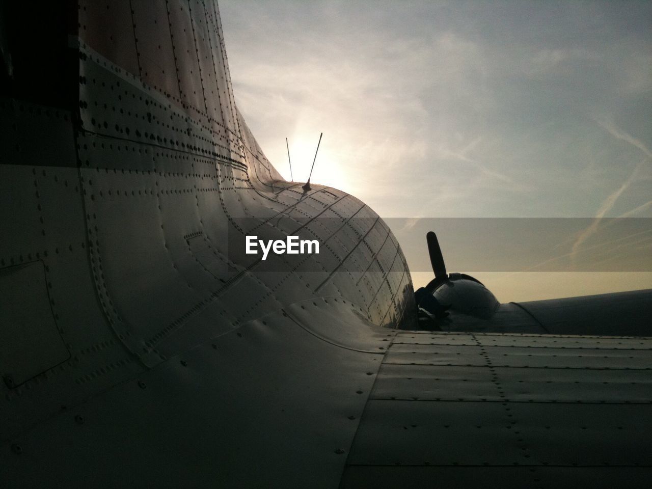 Cropped image of airplane flying in sky at sunset