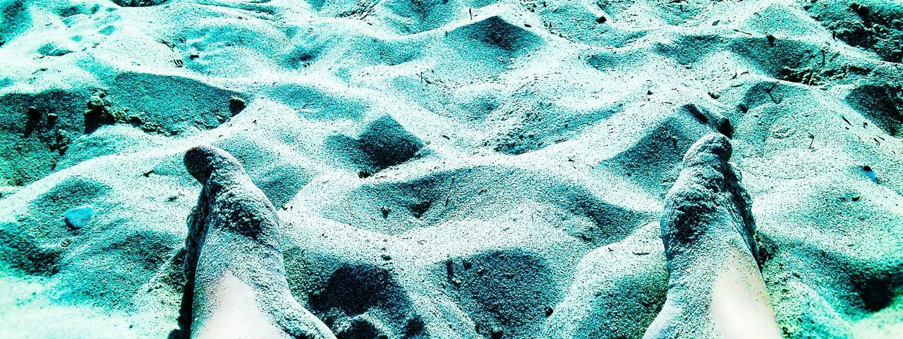 Cropped image of human leg covered with sand on beach
