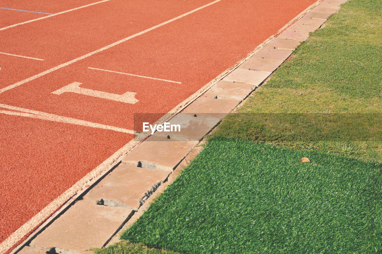 Empty running track by grassy field