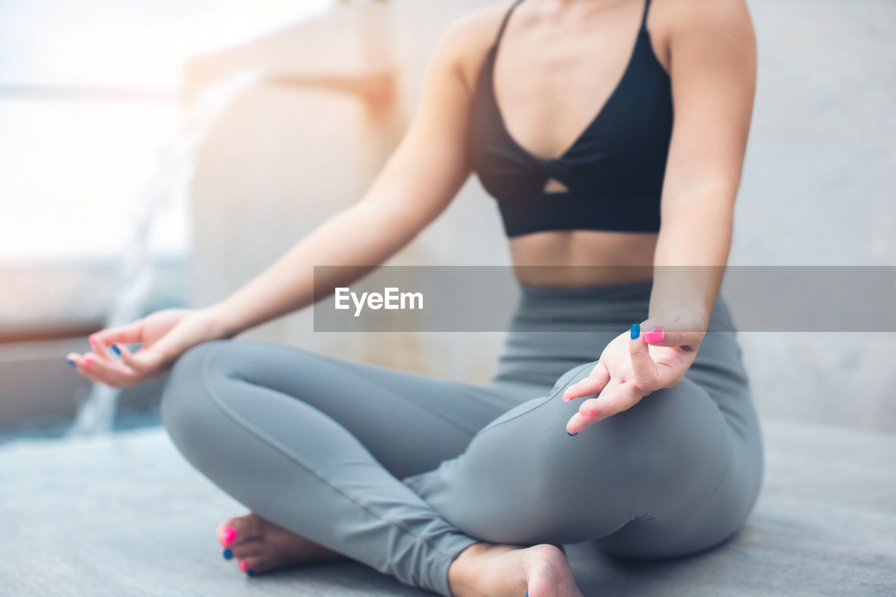 Low section of woman meditating indoors