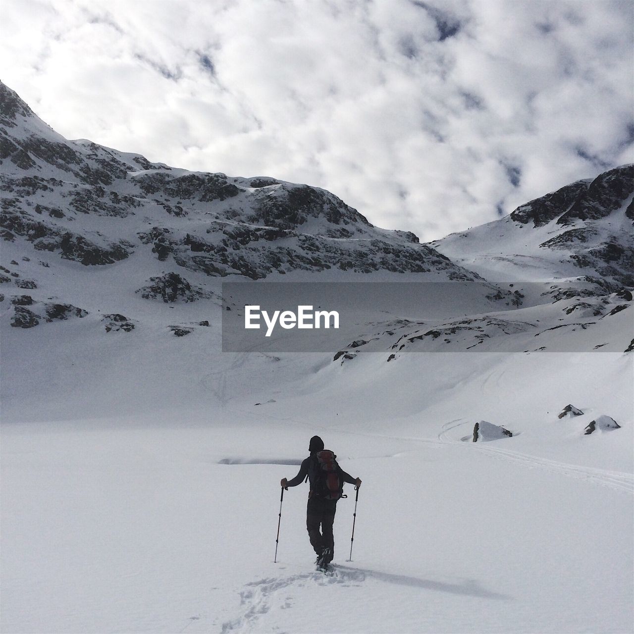 REAR VIEW OF PERSON SKIING ON SNOWCAPPED MOUNTAIN