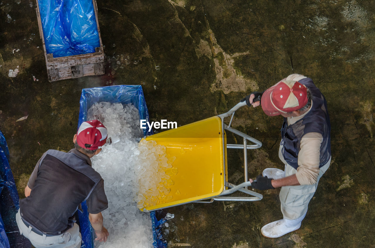 High angle view of people packing ice in plastic bag