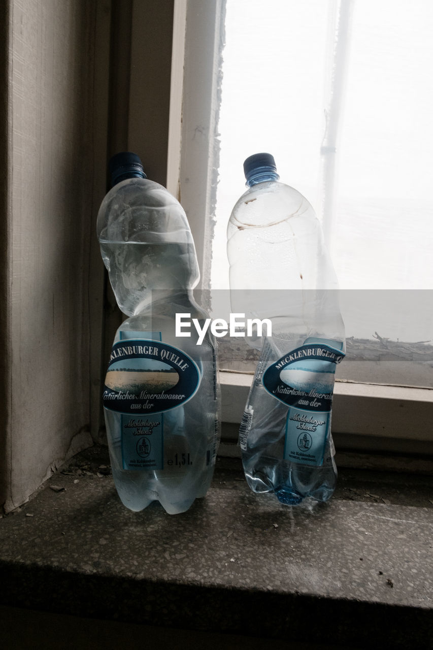 CLOSE-UP OF ABANDONED BOTTLE ON WINDOW