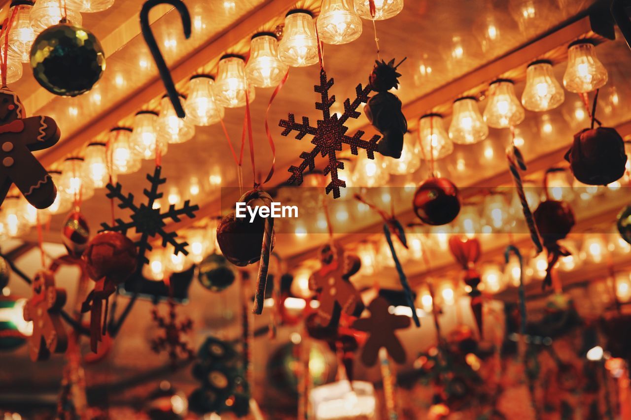 Low angle view of illuminated light bulbs and christmas decorations on ceiling