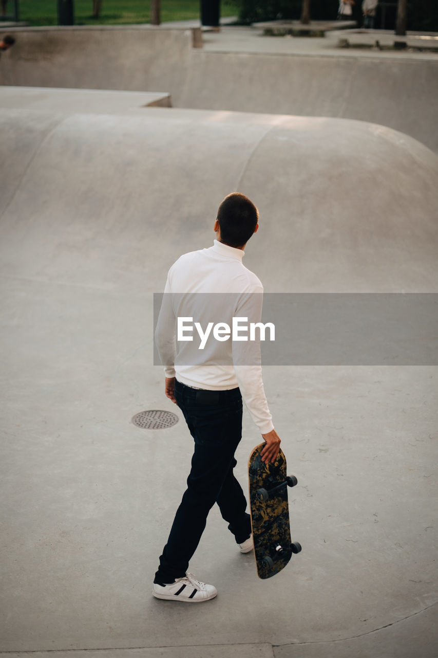 High angle view of man with skateboard walking at park