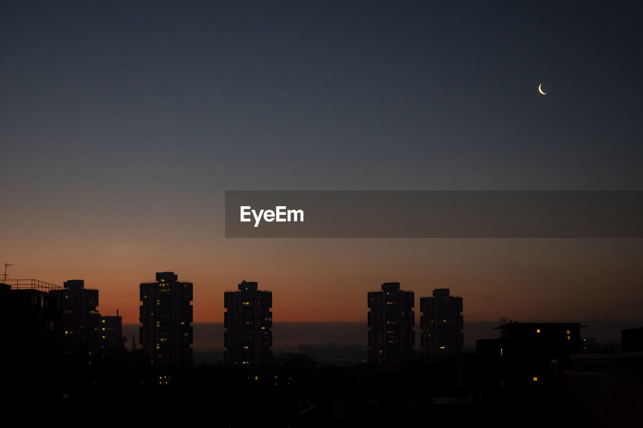 Silhouette buildings against sky at night