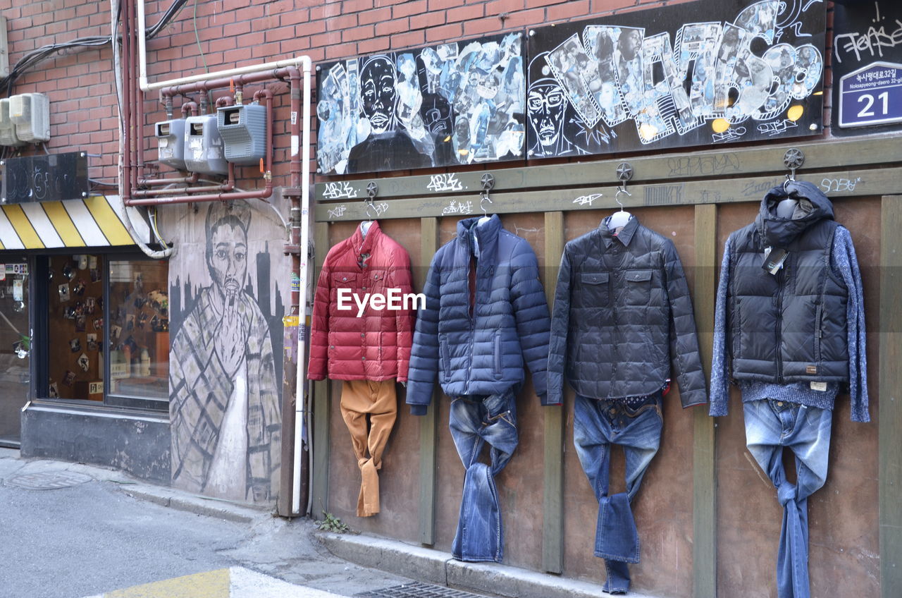 CLOTHES HANGING IN STORE FOR SALE AT STREET MARKET